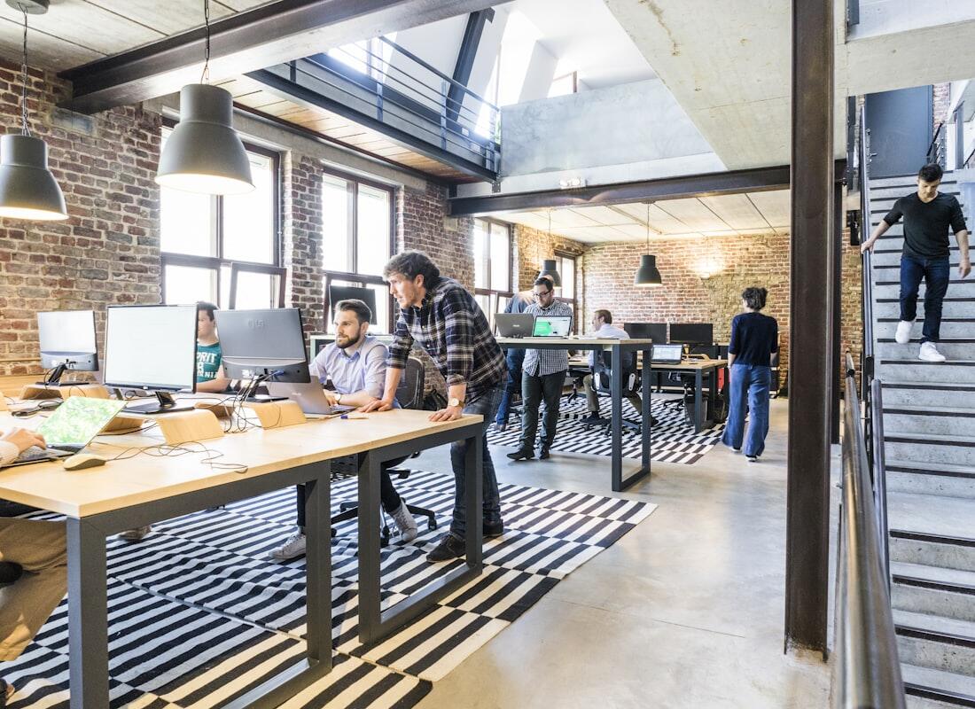 Area kerja kantor open space dengan meja kayu dan tanaman
