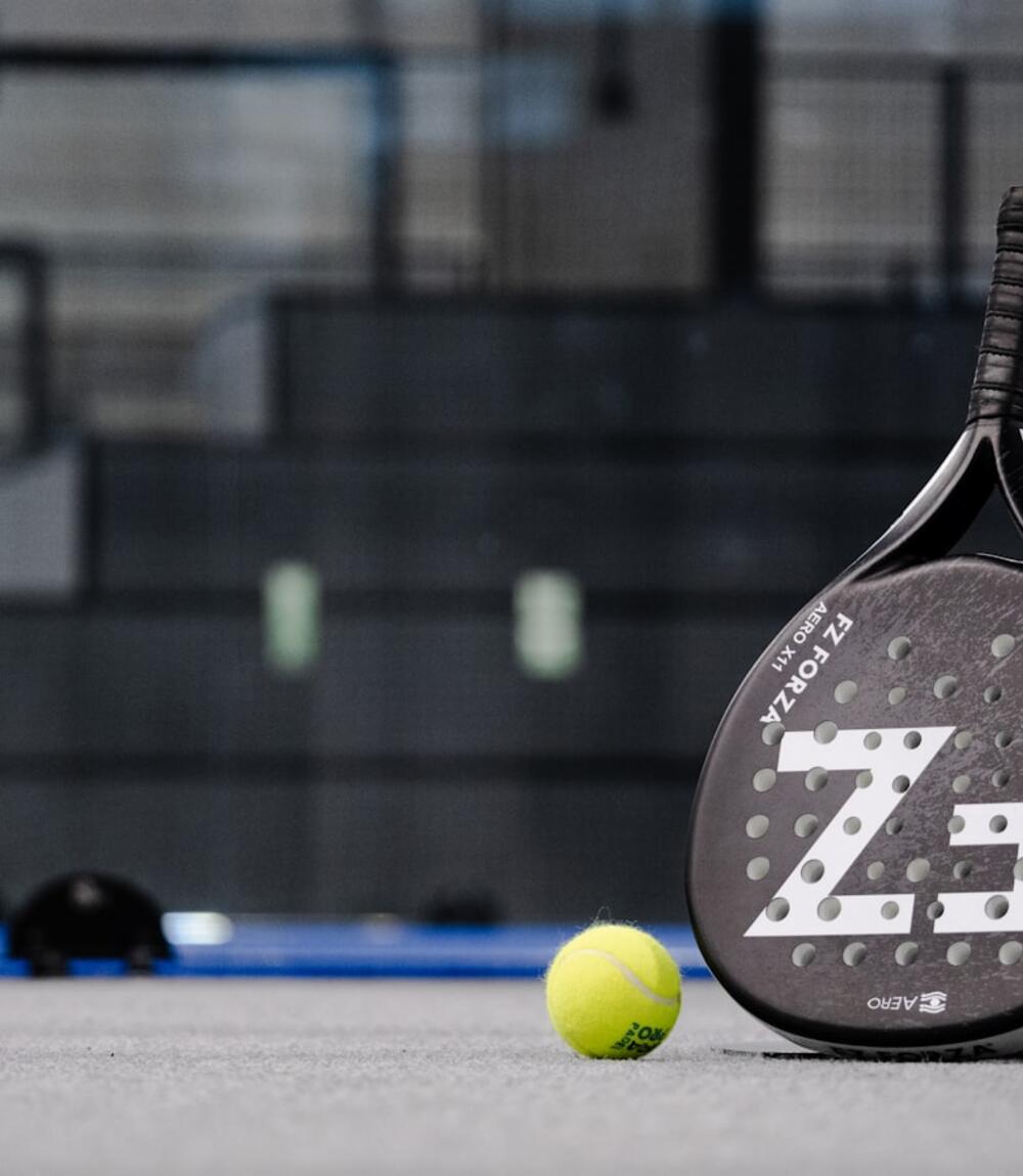 Raket dan bola padel bersandar