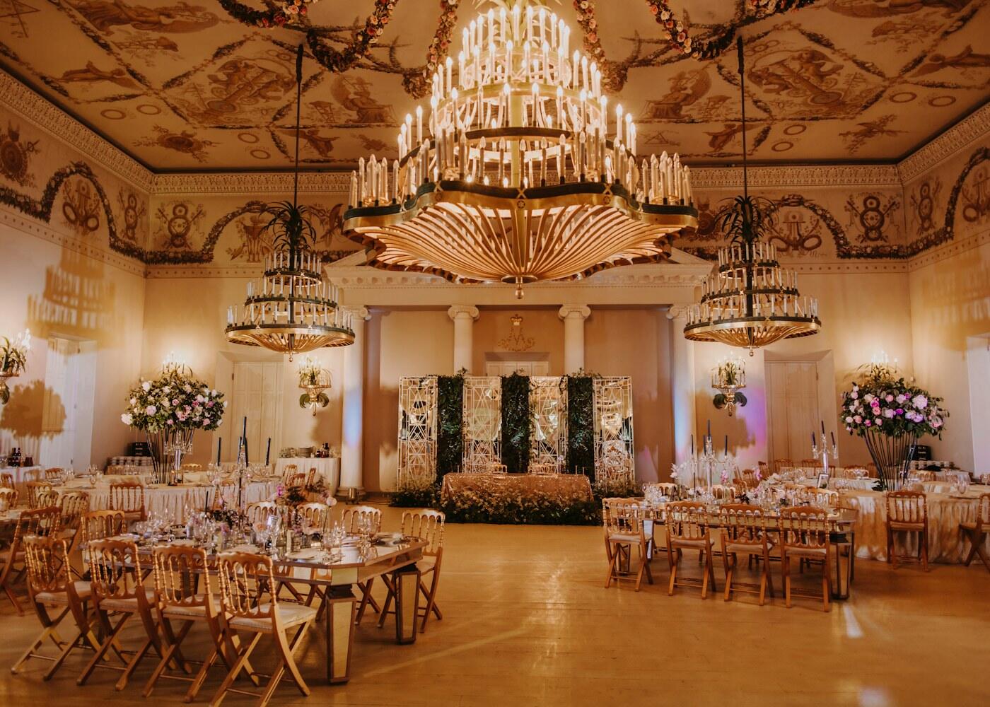 Grand ballroom pernikahan dengan chandelier dan meja tertata mewah